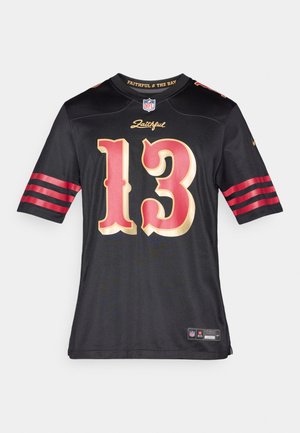 Melnas NFL kreklā ar zeltainu ciparu "13" un sarkani svītrām uz piedurknēm. Virs numura ir teksts "Faithful", un apakšmalā ir zīmola etiķete.