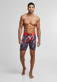 Caleçons boxeurs noirs avec des accents rouges, présentant un design graphique audacieux "100". Ceinture élastique avec un logo ; texture de tissu lisse.