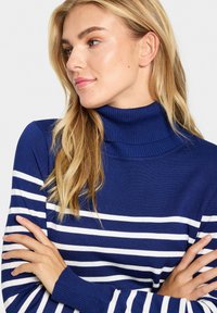 Marinblå polotröja med vita horisontella ränder, ribbade ärmslut och en mjuk textur, i en figurnära design.
