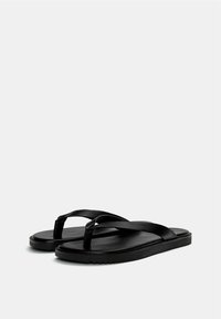 Infradito neri con una finitura opaca e testurizzata, dotate di due cinghie incrociate e una suola piatta. Design semplice senza ulteriori decorazioni.