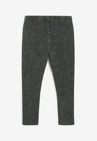 Mörkgröna leggings med en strukturerad yta, elastisk midja och smal passform. Tyget har ett subtilt, spräckligt mönster genom hela plagget.
