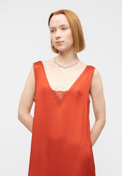 Κόκκινο σατέν φόρεμα με βαθιά λαιμόκοψη V, δαντέλα στο τελείωμα και λεπτές τιράντες. Λείος υφής, άνετη εφαρμογή και μινιμαλιστικός σχεδιασμός.