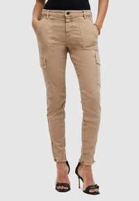 Beige cargobyxor med slim fit, som har flera fickor, fransade fållar och knappstängning. Tillverkade av bomullsblandat tyg.