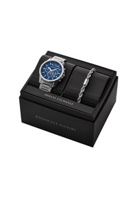 Orologio in acciaio inox argentato con quadrante blu e accenti argentati, abbinato a un bracciale in metallo intrecciato, presentato in una scatola nera.