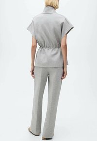Top grigio a maniche corte con colletto e vita con cordino abbinato a pantaloni grigi a palazzo. Tessuto liscio con vestibilità comoda.