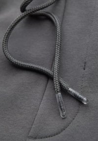 Graue Kapuzenpullover-Kordeln mit geflochtenem Textur, ausgestattet mit klaren Kunststoffspitzen. Der Stoff ist glatt mit einem subtilen Glanz.