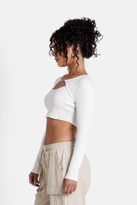 Korte witte top met lange mouwen en een keyhole uitsnijding, gecombineerd met beige cargo broeken met elastische taille. Soepele textuur, aansluitend ontwerp.