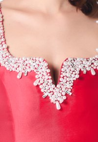 Robe en satin rouge avec un décolleté en V orné de perles blanches et de strass, créant un design texturé et orné le long de l'ourlet.