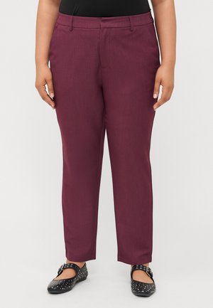 Burgundy trousers with a straight cut, made from smooth fabric. Features front pockets and a zipper closure. Worn with black studded flats.