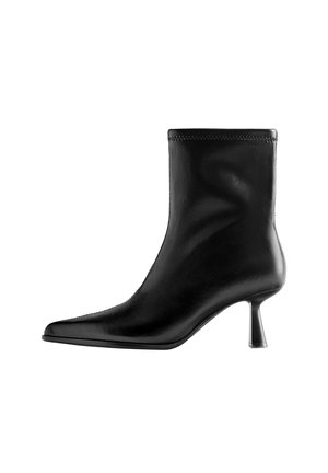 Bottine en cuir noir avec bout pointu et talon moyen et fin sur fond blanc.