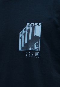 Μαύρο ύφασμα με λευκό γραφικό κτήριο, τη λέξη "BOSS" επάνω και κείμενο από κάτω που αναγράφει "OST BHF RECORDS" με κυκλικό λογότυπο.