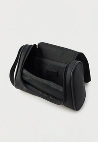 Μαύρο καλλυντικό τσαντάκι από υφή υφάσματος, με φερμουάρ, εσωτερική τσέπη από δίχτυ και ορθογώνιο σχήμα.