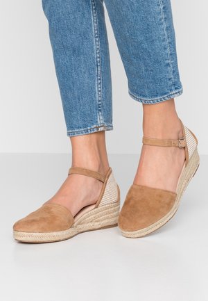 Brown suede espadrilles with braided rope sole, open back, and ankle strap; featuring a textured, beige mesh detail on the heel.