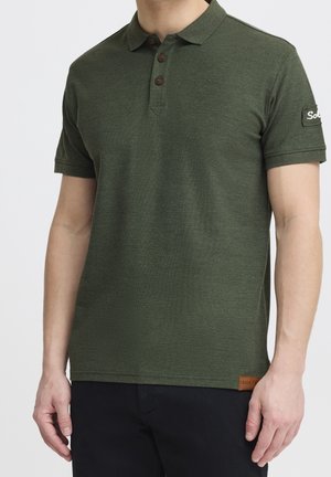 Polo shirt vert foncé en tissu texturé avec un col à trois boutons et des manches courtes. Écusson logo marron sur la manche et l'ourlet.