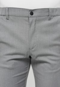Pantalones tejidos grises que presentan un cierre de botón, pasadores para cinturón y bolsillos frontales con una textura suave y un ajuste entallado.
