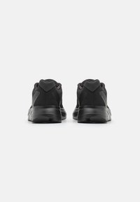 Scarpe sportive nere con tomaia in rete, suola imbottita e design minimalista caratterizzato da texture lisce e accenti sottili.