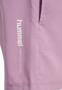 Lila sportbroek met een gladde textuur. Voorzien van een wit logo en labeling, een zijzak en nette stikdetails.