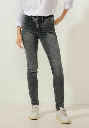 Jean skinny en délavé noir, avec une taille haute, un design à cinq poches, des détails de couture subtils et une texture lisse.