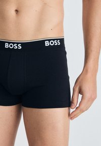 Schwarze Boxershorts mit einem weißen Logo-Bund. Aus glattem Stoff, passgenauem Design und mittellanger Oberschenkel-Länge.