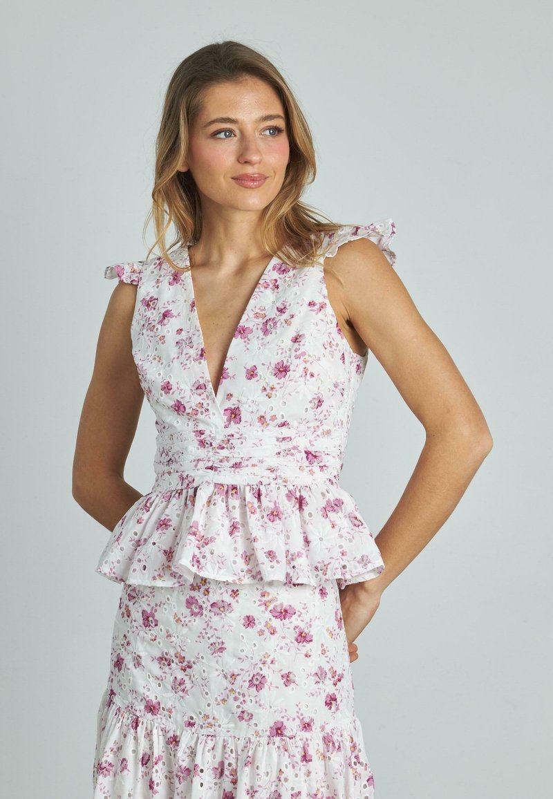 Abito floreale con scollatura a V profonda, spalline arricciate e vita a peplo. Tessuto bianco con fiori rosa e viola e dettagli in pizzo.
