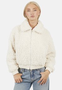 Crème-kleurige fleece bomberjack met een gestructureerd, fluffy oppervlak, voorzien van een met kraag en ribgebreide manchetten en zoom. Ritsluiting.