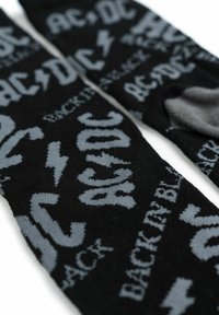 Calze nere con testo grigio e branding AC/DC, motivi a fulmine, motivo lavorato a maglia, texture liscia. Ideali per un abbigliamento casual.