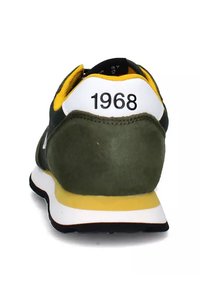 Sneaker verde in suede con accenti gialli, tallone bianco con la scritta "1968" e suola multilivello in nero e giallo.
