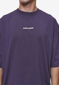 Violets kokvilnas T-krekls ar apaļu kakla izgriezumu, īsām piedurknēm un "PEGADOR" logo baltā izšuvumā uz krūtīm. Mīksta tekstūra.