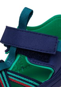 Scarpe con una tomaia blu navy dalla finitura testurizzata, interno verde e una fascia in Velcro per una chiusura sicura. Accentuate da strisce multicolori.