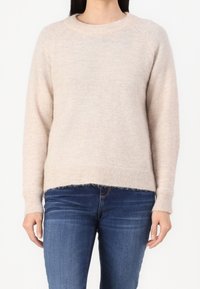 Hellbeige Strickpullover mit runder Ausschnitt, langen Ärmeln und geripptem Saum. Weiche Textur, leicht verkürzte Länge und lockere Passform.