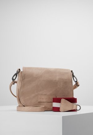 Beige perforeret crossbody-taske med aftagelig rem og ekstra rød og hvid stofrem på hvid overflade mod ensfarvet baggrund.