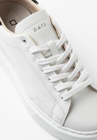 Hvide sneakers lavet af glat læder med hvide snørebånd, sølvfarvede øjekanter og en tekstureret sål. Har "D.A.T.E." branding på tungen.