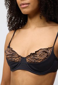 Μαύρο σουτιέν με κύπελλα σε λεοπάρ σχέδιο, με ραφές με βολάν, λεπτές ρυθμιζόμενες τιράντες και λεία υφή.
