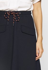 Svarta träningsshorts i texturerat tyg, med elastisk midja och en kontrasterande snörning. Två sidofickor som är vertikalt placerade.