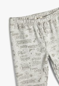 Szare, elastyczne legginsy z gumką w talii, zdobione różnymi motywacyjnymi hasłami w metalicznym srebrnym druku. Gładka, miękka faktura.