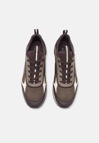 Sneaker con una combinazione di rete marrone e oliva, con accenti marrone scuro, punta rotonda, superficie testurizzata e strisce bianche a contrasto.