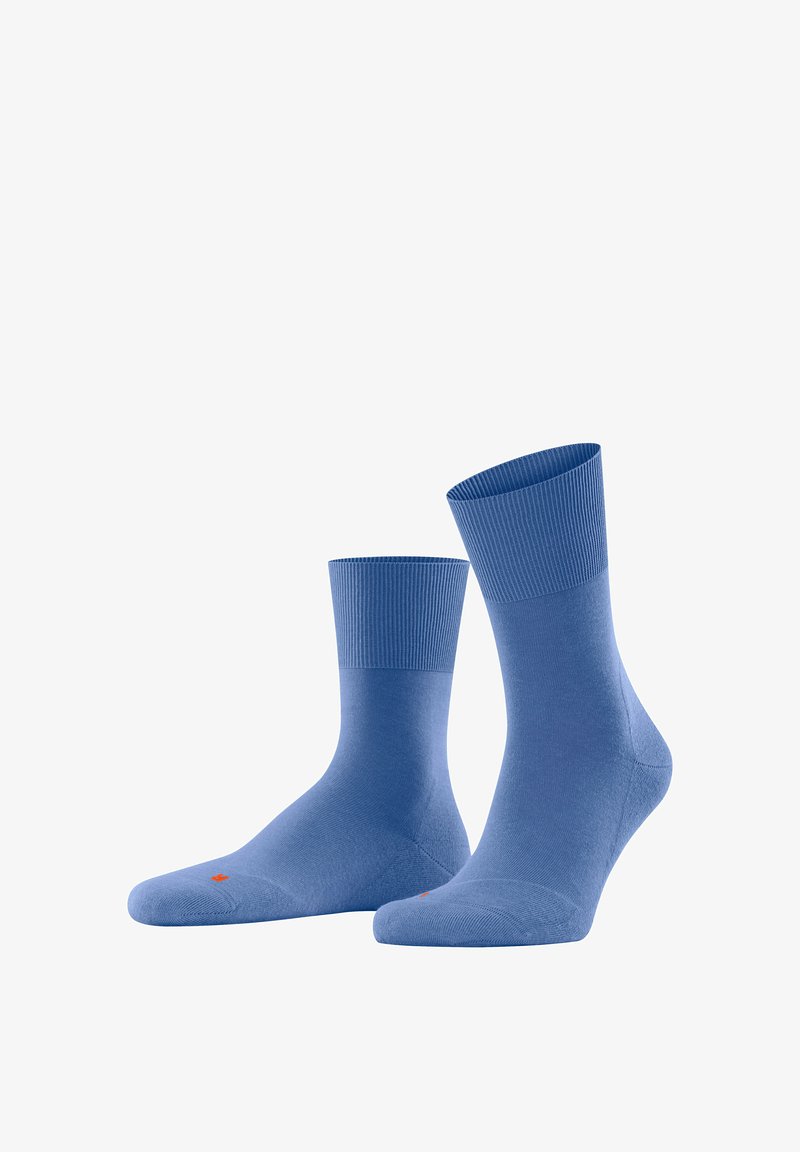 Niebieskie skarpetki z mieszanki bawełny mają żebrowany mankiet, gładką teksturę i wzmocniony czubek. Na podeszwie widoczny jest mały pomarańczowy logo.
