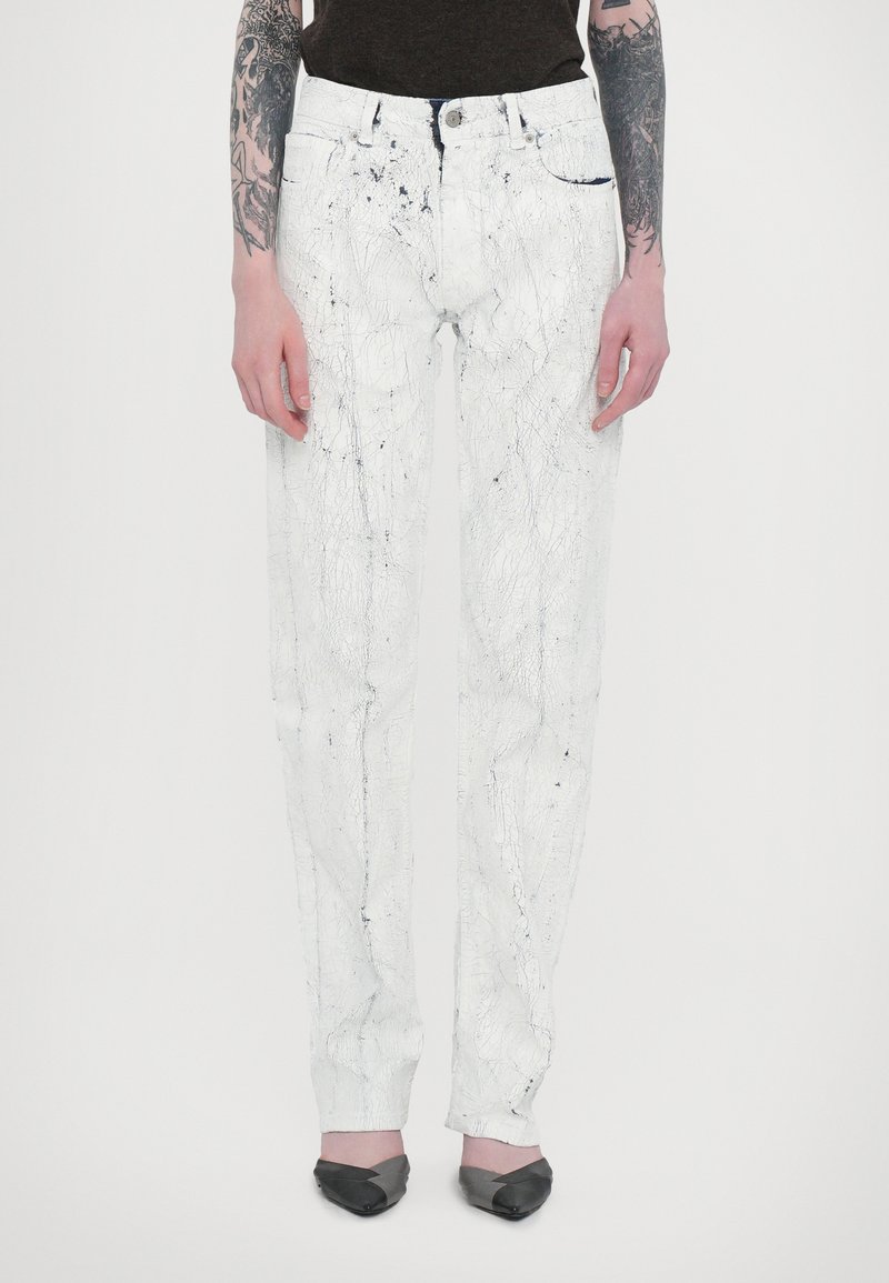 White denim trousers with a textured surface featuring black splatter patterns. Straight-leg design with a button and zipper closure.