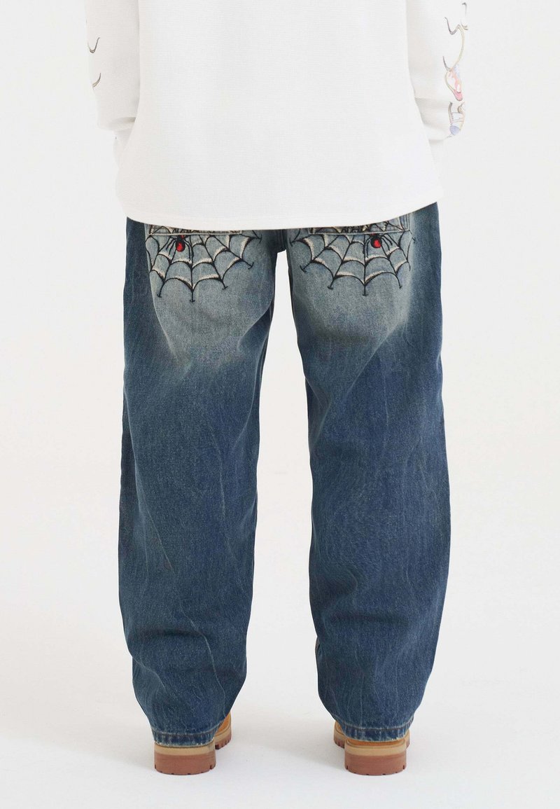 Denimjeans i mörkblått med lös passform, med spindelnätsbroderi på bakfickorna och en texturerad yta.