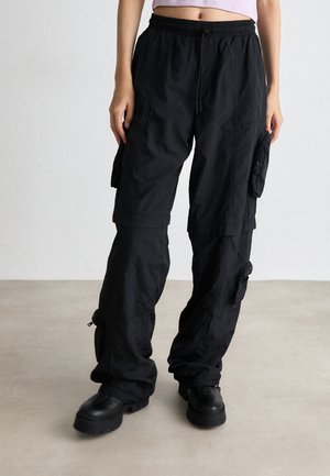 Pantalons cargo noirs avec une coupe décontractée, taille élastique, plusieurs poches latérales et zips aux chevilles ; fabriqués en tissu léger.