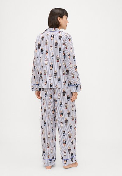 Conjunto de pijama em algodão com padrão riscado e figuras de desenhos animados, de mangas longas e camisa abotoada, complementado por calças combinando.