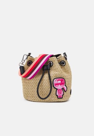 Geflochtene Strohtasche mit schwarzem Kordelzug, rosa-rot gestreiftem Regenbogen-Schulterriemen und einem rosa Cartoon-Figuren-Patch auf der Vorderseite.