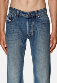 Klassiska blå denimjeans med avslappnad passform, synlig sömnad, fem fickor och en blekt yta för en sliten look.