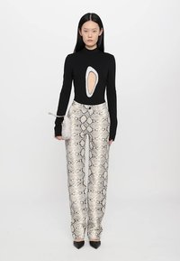 Black long-sleeve top with an oval cutout, paired with light-colored snake-print pants and black pointed heels. Small fluffy handbag.