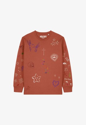 Giovane uomo che indossa una maglia marrone a maniche lunghe con disegni colorati in stile disegnato a mano, tra cui uccelli, stelle, un teschio e un cuore con raggi.