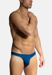 Blaue Herren-Unterhosen mit glatter Textur, elastischem Bund und konturiertem Vorderteil. Mit minimalen Nähten und enganliegendem Schnitt.