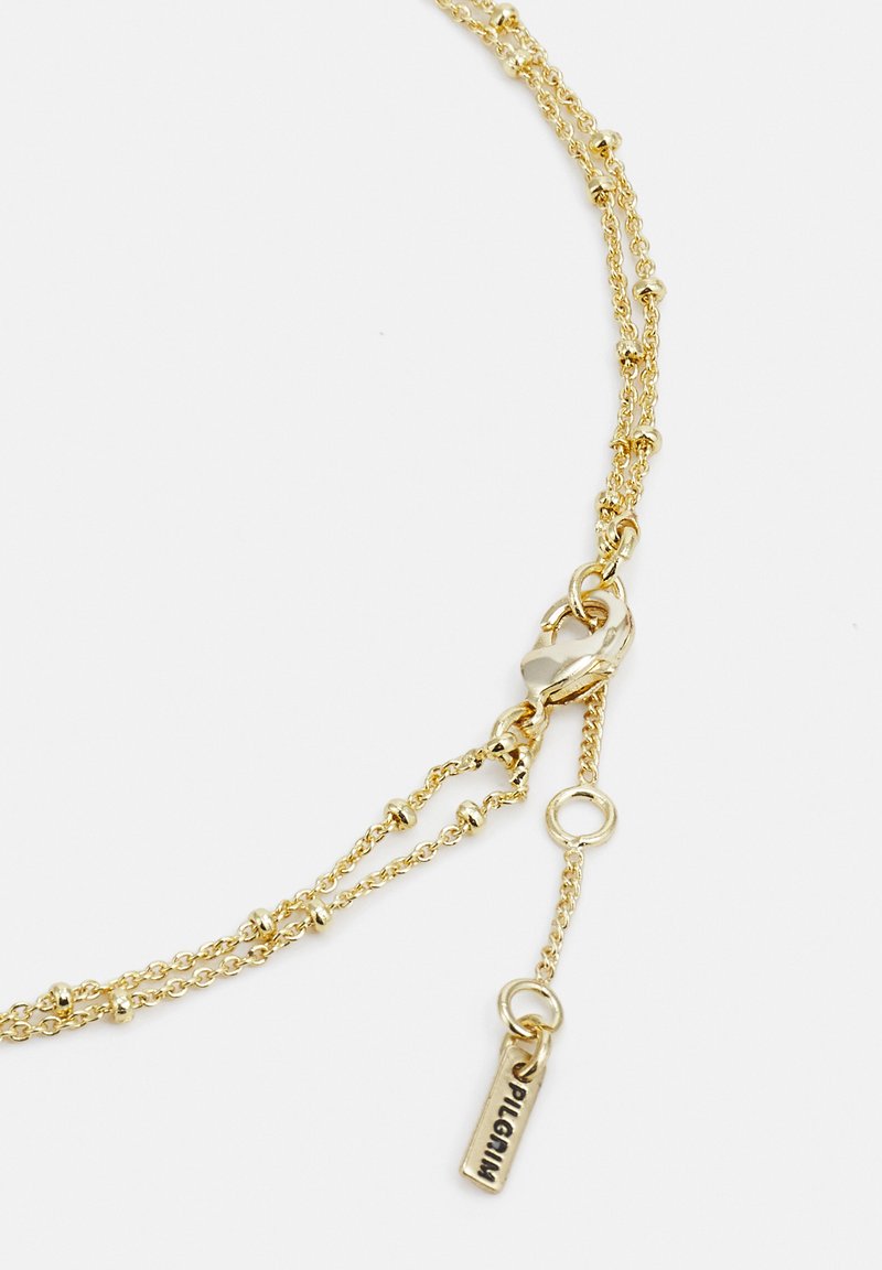 Gold-tone layered chain necklace featuring textured links, small bead accents, and a lobster clasp with a brand tag.