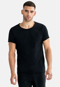 Svart bomull T-shirt med rund hals, korta ärmar och en figurnära design, mot en neutral bakgrund.
