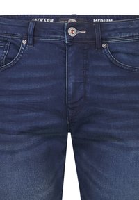 Tummansiniset farkut, joissa on hieman haalistumista, viisi taskua, metallinappikiinnitys ja ommeltuja yksityiskohtia taskujen ympärillä.