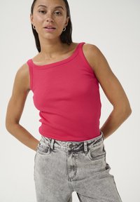 Top aderente rosa a coste con spalline larghe, abbinato a jeans in denim di un grigio chiaro con lavaggio acido a vita alta.